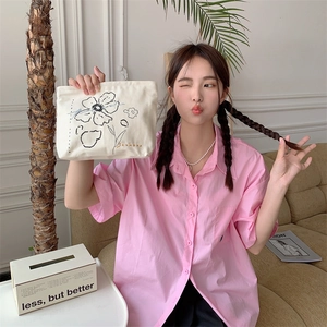 Detailed shot of beige canvas makeup bag with floral embroidery held by a female model
