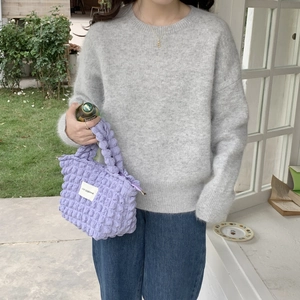 Detail of purple bubble textured canvas handbag shown with a grey knit sweater and jeans