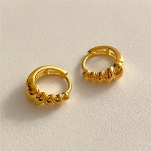 Detailed view of golden croissant hoop earrings with elegant spiral texture and metallic finish