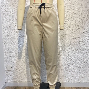 Dettaglio dei jogger in ecopelle beige con vita elastica e coulisse nera regolabile