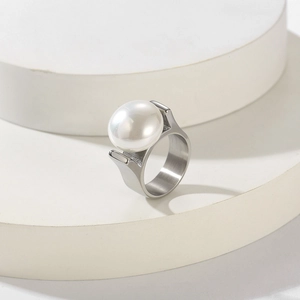 Nahaufnahme eines breiten Edelstahlrings mit einer großen weißen Muschelperle