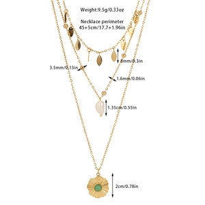 Detailed view of layered gold necklace with green stone flower pendant and leaf charms
