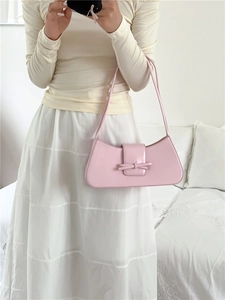 Close-up of light pink baguette bag with decorative bow detail held by model