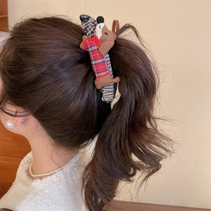 Detail of cute fabric dachshund dog hair clip with red and blue plaid pattern on hair