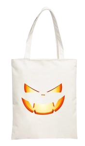 Detail of white canvas tote bag featuring a 2D digital orange glowing pumpkin face print