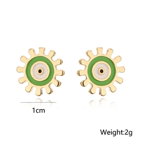 Detail of 1cm 18K gold gear earrings with green evil eye enamel and 2g weight text