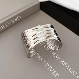 Close-up of wide silver cuff bracelet with irregular wrinkled texture on a book