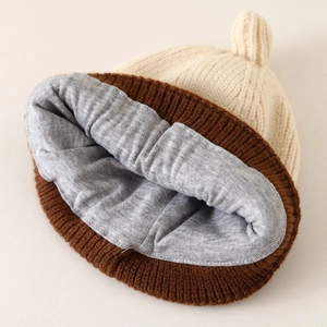 Knitted baby beanie with top knot and warm grey lining in beige and brown colors