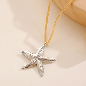 Gros plan du pendentif étoile de mer vintage argenté sur un cordon en daim jaune