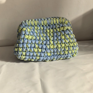 Detailed texture of blue and yellow handmade crochet clutch bag in knitted fabric