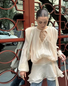 Detailed texture of pleated cream satin dress with elegant puff sleeves for women