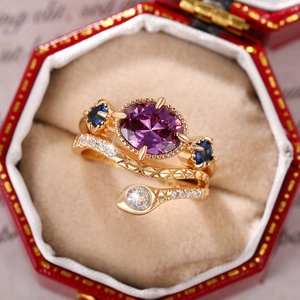 Exotic two-piece ring set with purple oval gemstone and gold snake ring in jewelry box