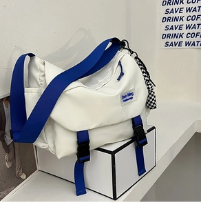 Detail of white nylon messenger bag with blue straps and black buckle closure