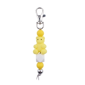 Detail of yellow silicone bear keychain with beads and silver lobster clasp on white background