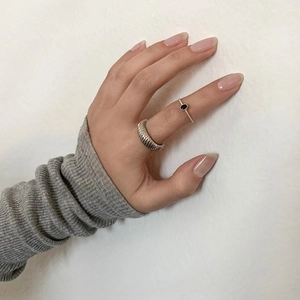 Detail of silver twisted croissant ring and minimal ring with oval black gemstone