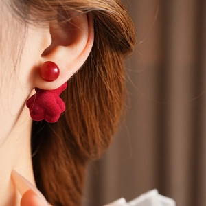 Close-up of a model wearing red velvet floral drop earrings with silver needle post