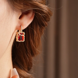 Macro de boucles d'oreilles dorées avec pierre rouge rectangulaire et cadre en métal