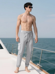 Detail of light gray cargo pants featuring adjustable drawstring waist and large side pockets