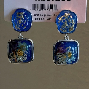 Detail of vintage resin earrings with blue dried flowers and gold leaf in silver frames