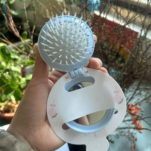 Close-up of a blue foldable mirror comb with candy pattern and massage bristles