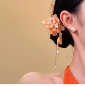 Detailed shot of an elegant peach fabric flower hair clip with pearl tassels on a model