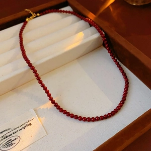 Detail of red beaded necklace with golden lobster clasp in a wooden jewelry box