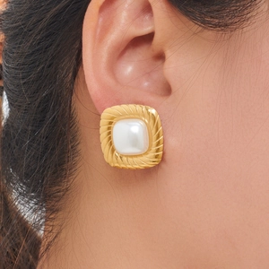Close-up of vintage square gold earrings featuring a white pearl inlay on model ear