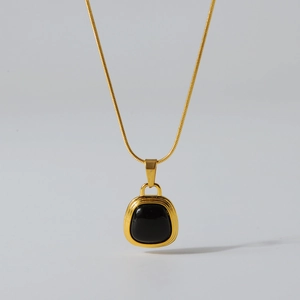 Detail of square black stone pendant on a delicate gold snake chain necklace