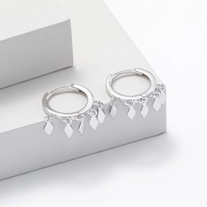 Macro view of S925 sterling silver hoop earrings with rhombic tassel pendants on a pedestal