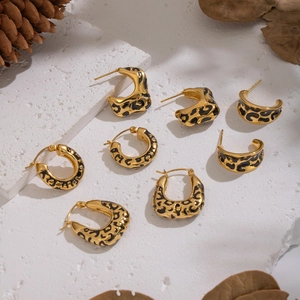 Golden leopard print hoop earrings in geometric irregular patterns on a marble surface
