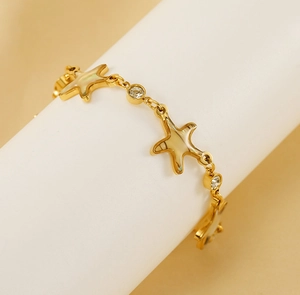 Detailed shot of starfish charms and inlaid shell in 18K gold-plated steel bracelet