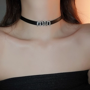 Gros plan d'un choker en similicuir noir avec pendentif lettre en cristal brillant