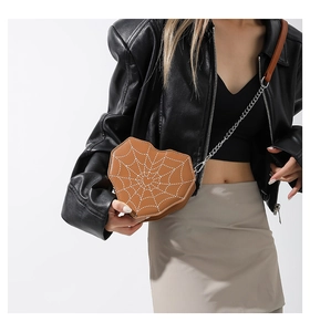 Detalle del bolso marrón en forma de corazón con diseño de telaraña y correa de cadena