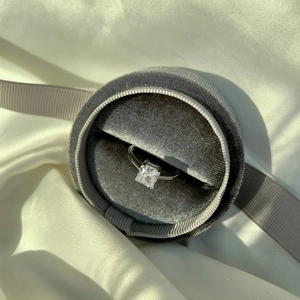 Detailed view of square cut diamond ring in silver setting inside a gray velvet jewelry box