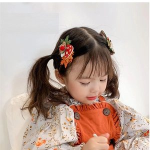Close-up of cute mushroom hair clip worn by a young girl with autumn leaf accents