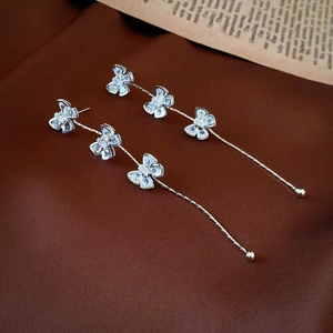 Detail of silver bow tassel earrings with sparkling cubic zirconia on brown fabric
