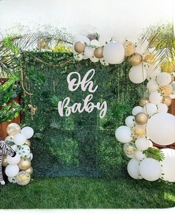 Détail de l'enseigne en bois Oh Baby sur mur d'herbe avec arche de ballons or et blanc
