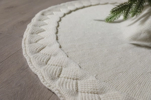 Close-up of cream white knitted Christmas tree skirt with thick cable knit border texture