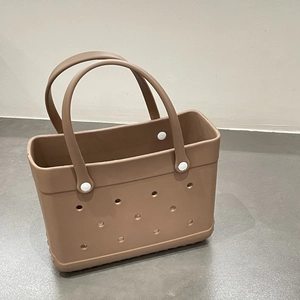 Close-up detail of a brown EVA beach tote bag featuring a perforated hole design and white rivets.