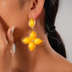 Close-up of vintage gold hollow oval earrings with yellow floral drop on a model
