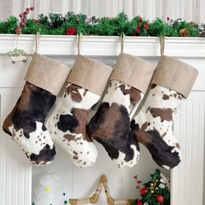 Close-up of four plush cow print Christmas stockings on a white fireplace mantel