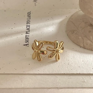 Detail of gold open ring featuring double daisy flower design on artistic paper
