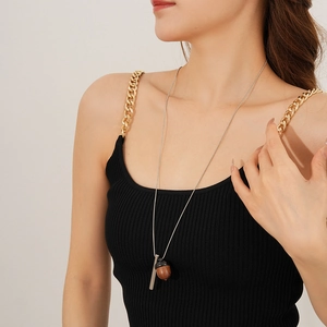 Close-up of long necklace featuring silver bar and dark brown wooden acorn pendant
