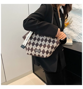 Detail of rhombic pattern tote bag with wide strap and fashion logo for daily commute