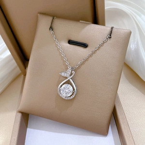 Close-up of silver fishtail pendant with sparkling crystals on a beige jewelry card