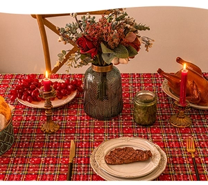 Close-up of red plaid Christmas tablecloth with candles and festive holiday table setting