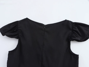 Dettaglio di un top nero da donna con cerniera posteriore invisibile e maniche a volant