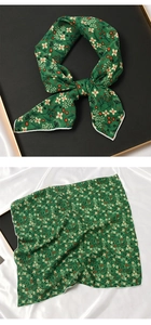 Détail d'un foulard en coton vert avec motifs de fleurs blanches et baies rouges