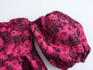 Detail of dark red jacquard fabric dress featuring floral pattern and puff sleeve design