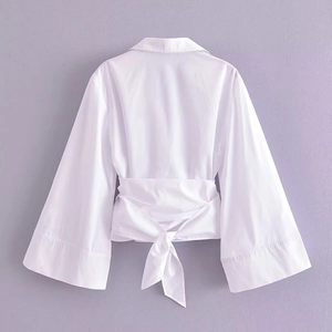 Blouse blanche élégante à cache-cœur, manches évasées et taille nouée au dos